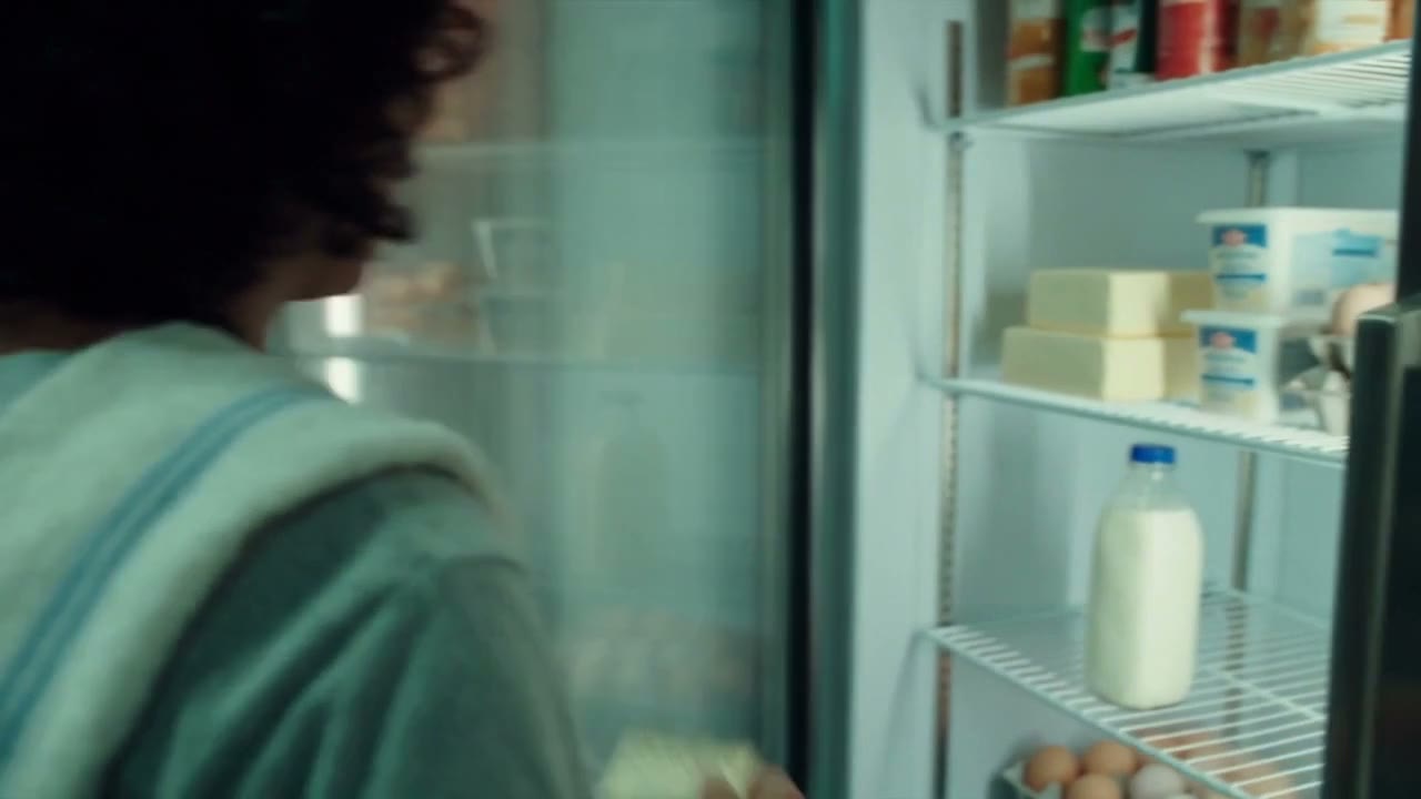 A fridge shelf with a single bottle of milk left