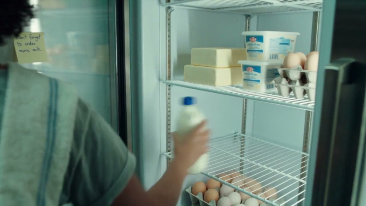 A baker taking a bottle of milk from the fridge
